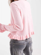 Pink sweater with ruffled hem worn by a person